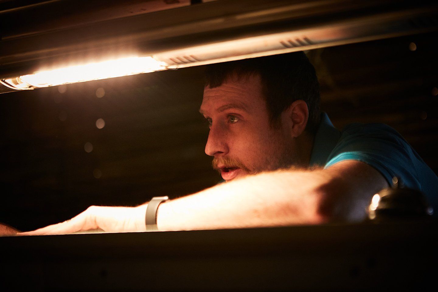 A man is looking out of an oven with a surprised look on his face.