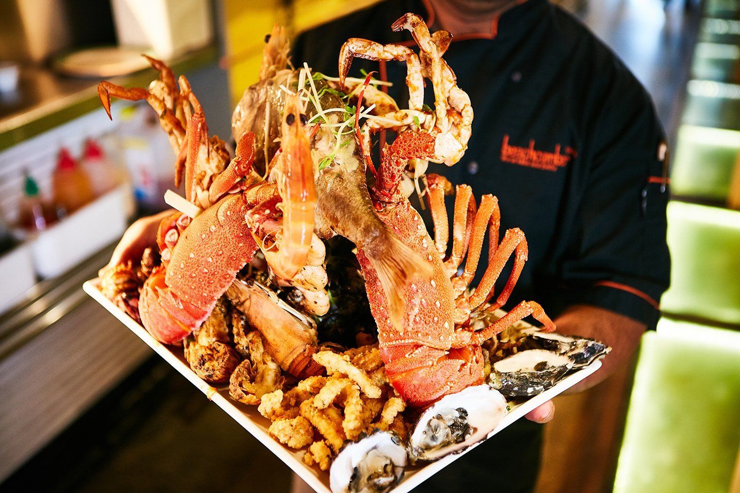 A chef is holding a plate of seafood and french fries.