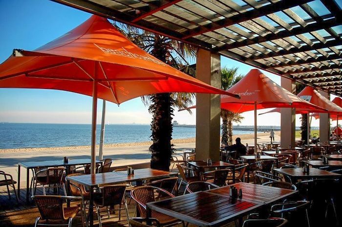 A restaurant with tables and chairs and umbrellas overlooking the ocean