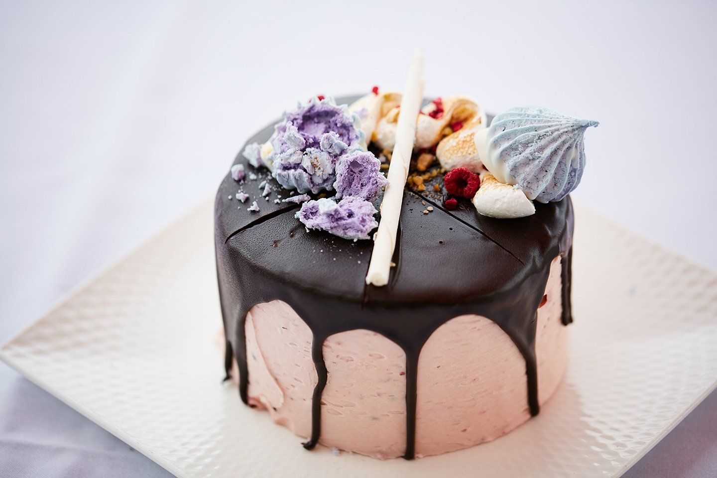 A cake with chocolate icing and flowers on it is on a white plate.