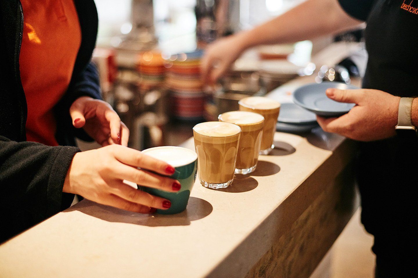 A woman is taking a cup of coffee from a barista.