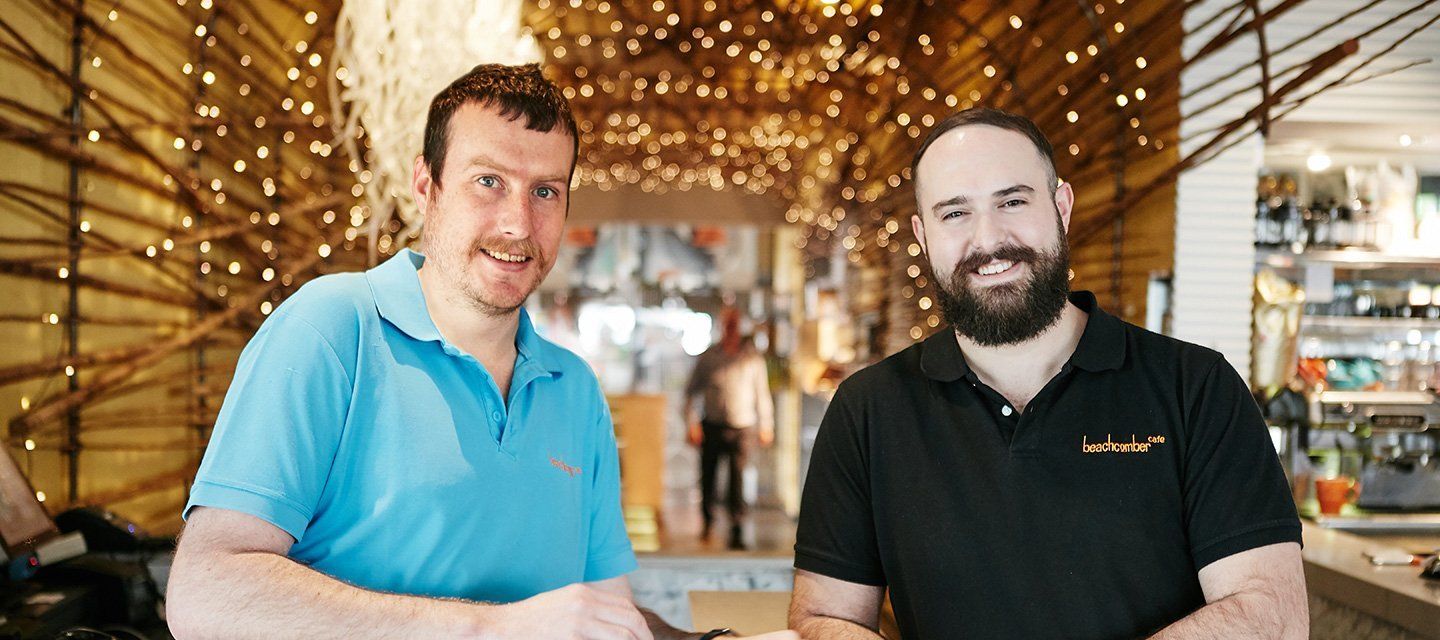Two men are standing next to each other in a restaurant.