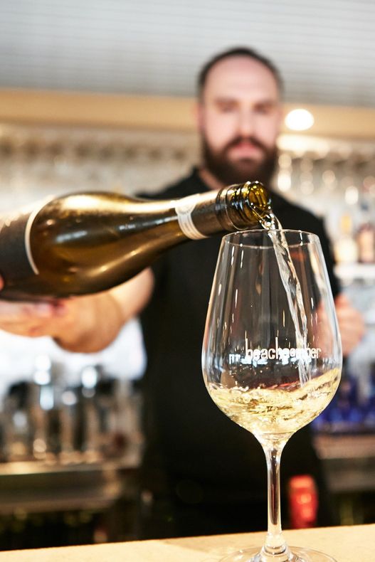 A man is pouring a glass of wine from a bottle.