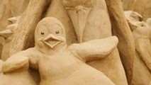 A close up of a sand sculpture of a penguin.