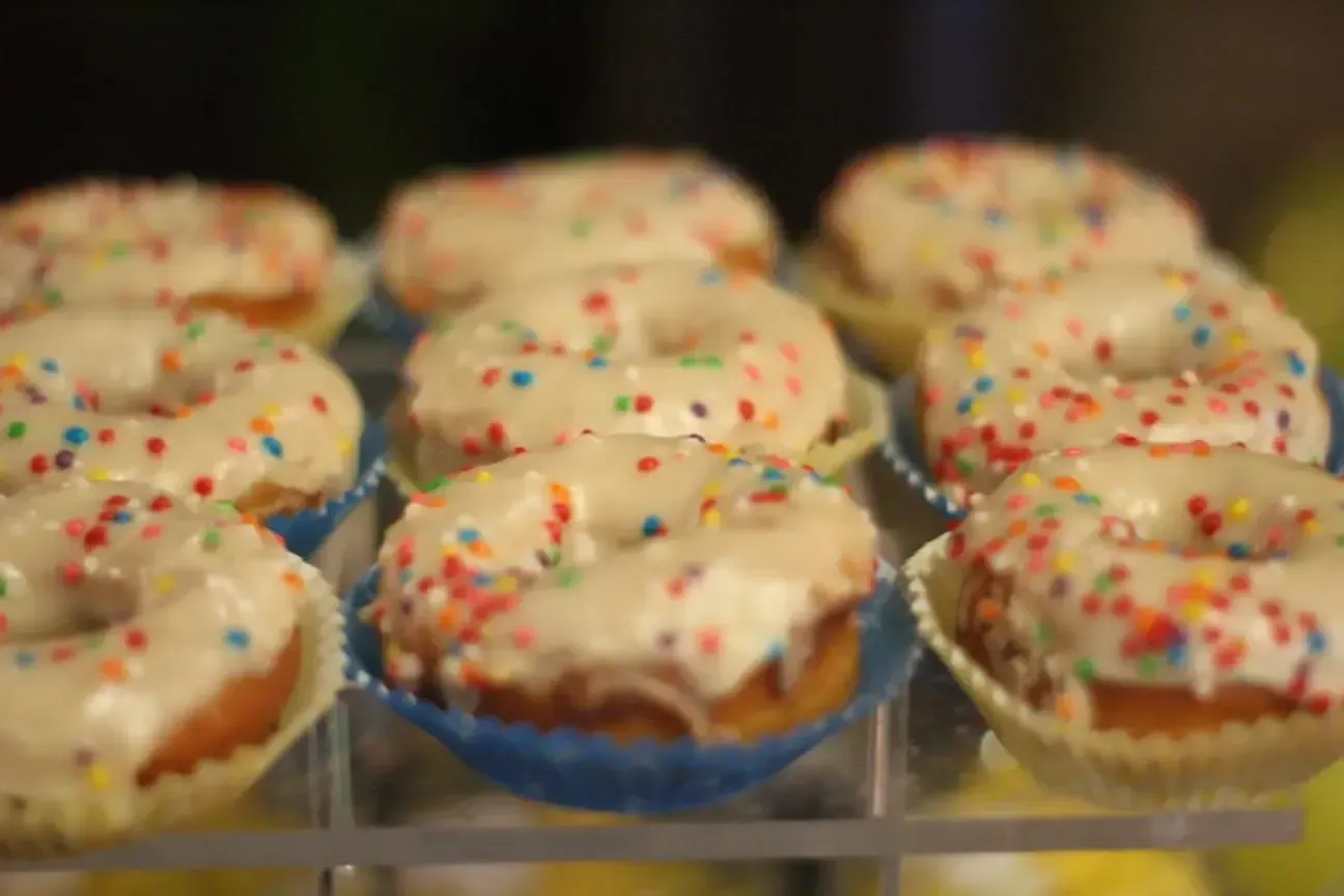 Una exhibición de donas con glaseado blanco y chispas.