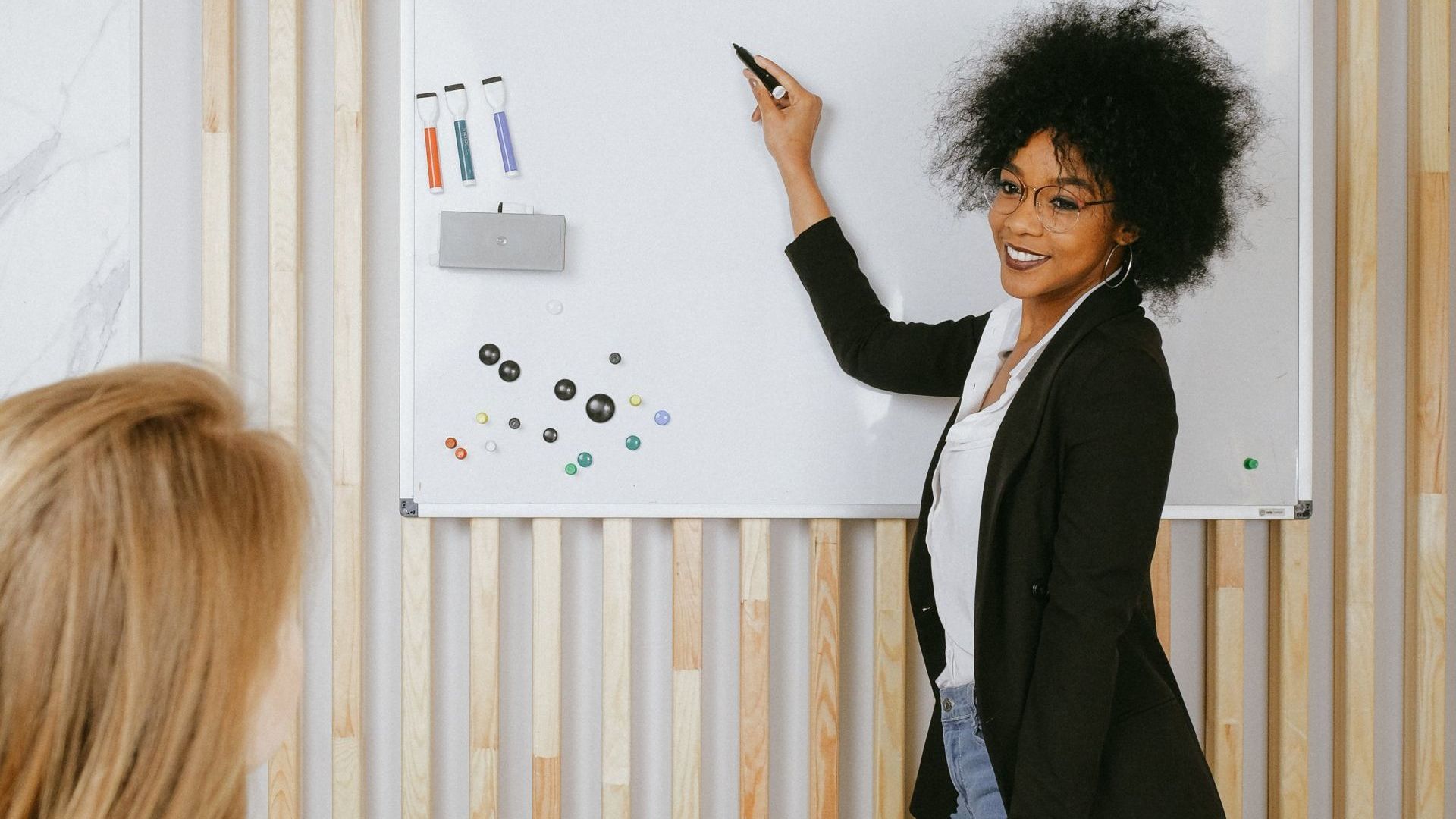 A woman is standing in front of a whiteboard giving a presentation.