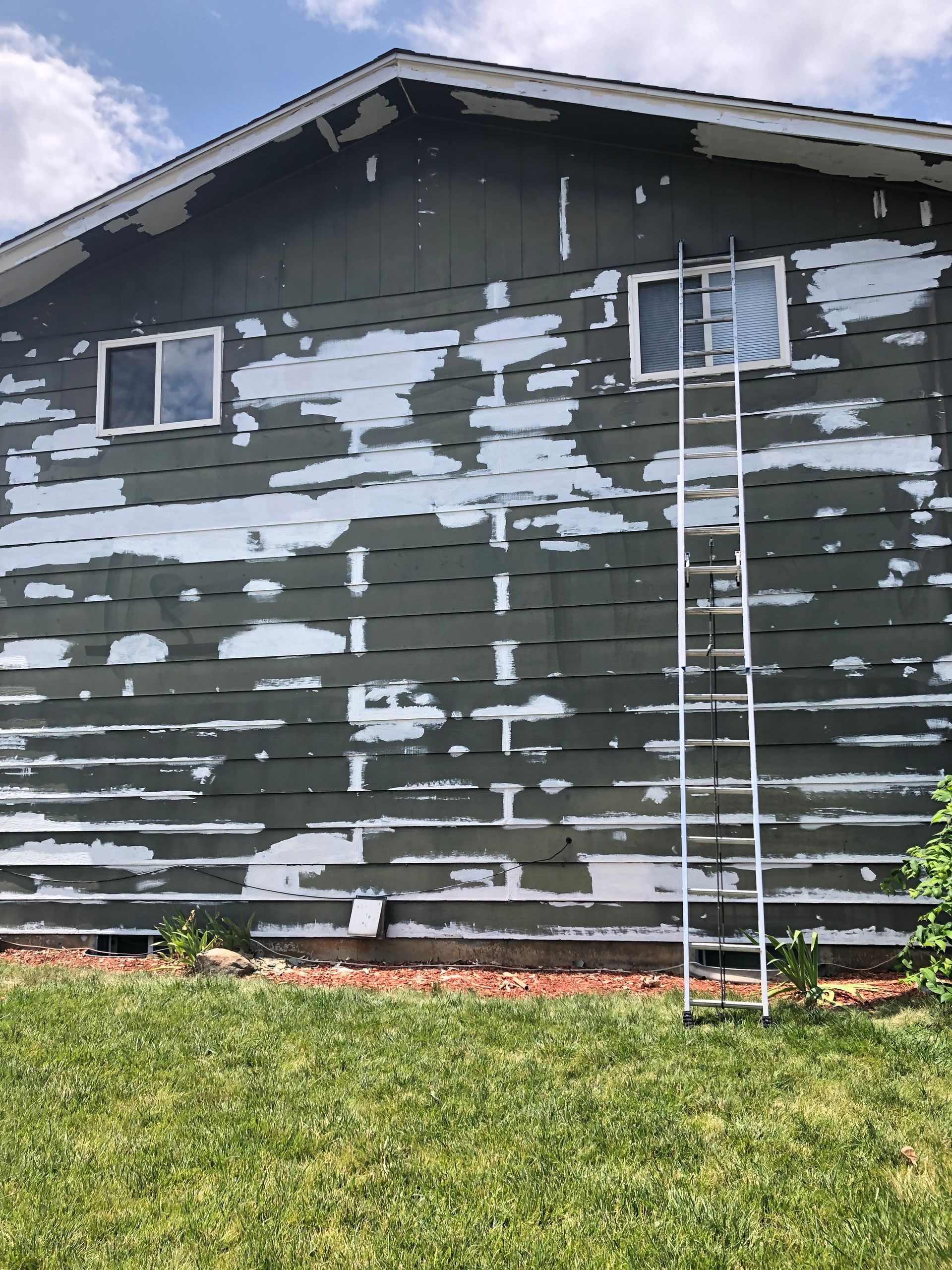 A Ladder Is Sitting On The Side Of A House That Is Being Painted