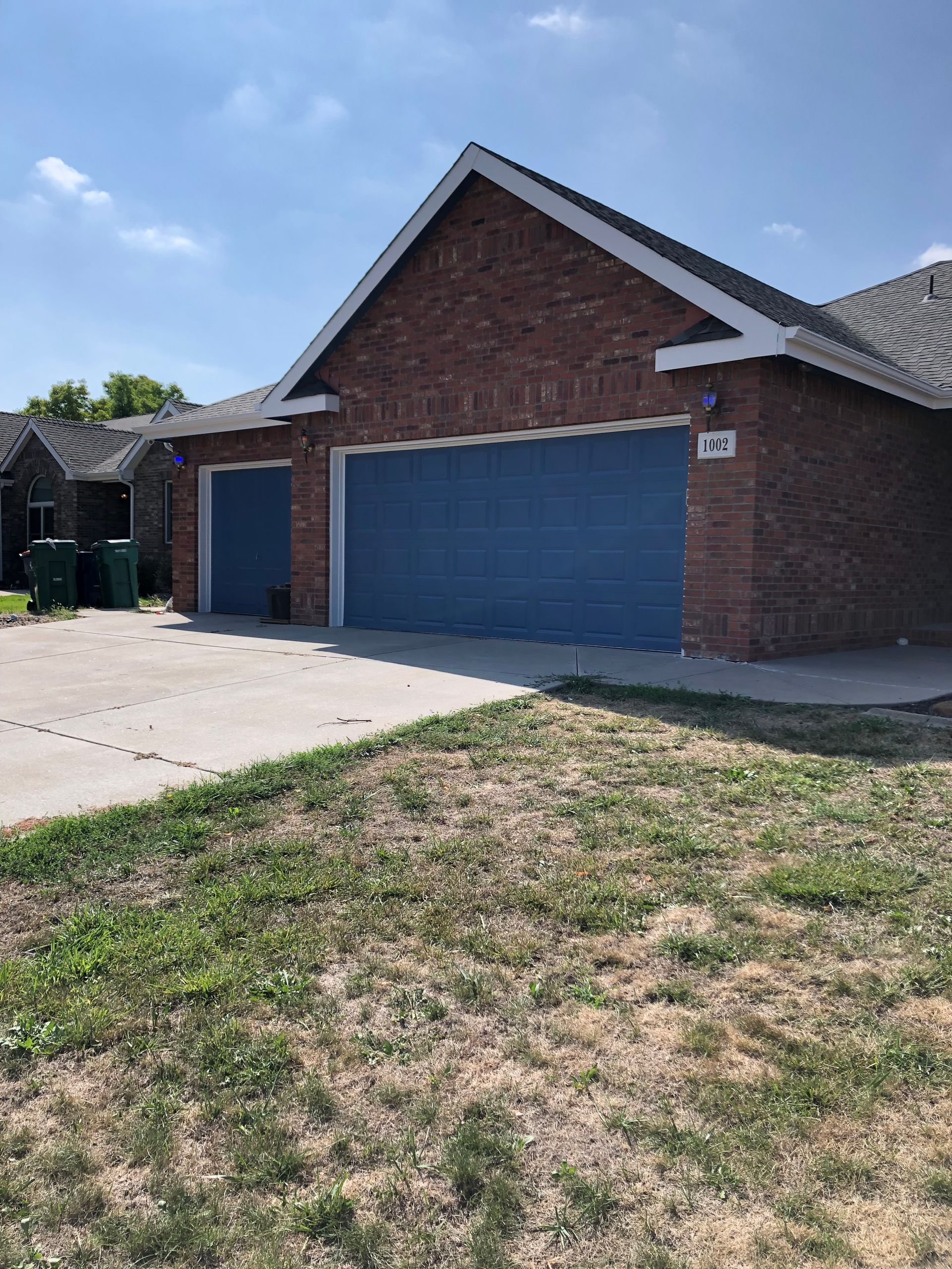 A Brick House With A Blue Garage Door And A Lawn In Front Of It