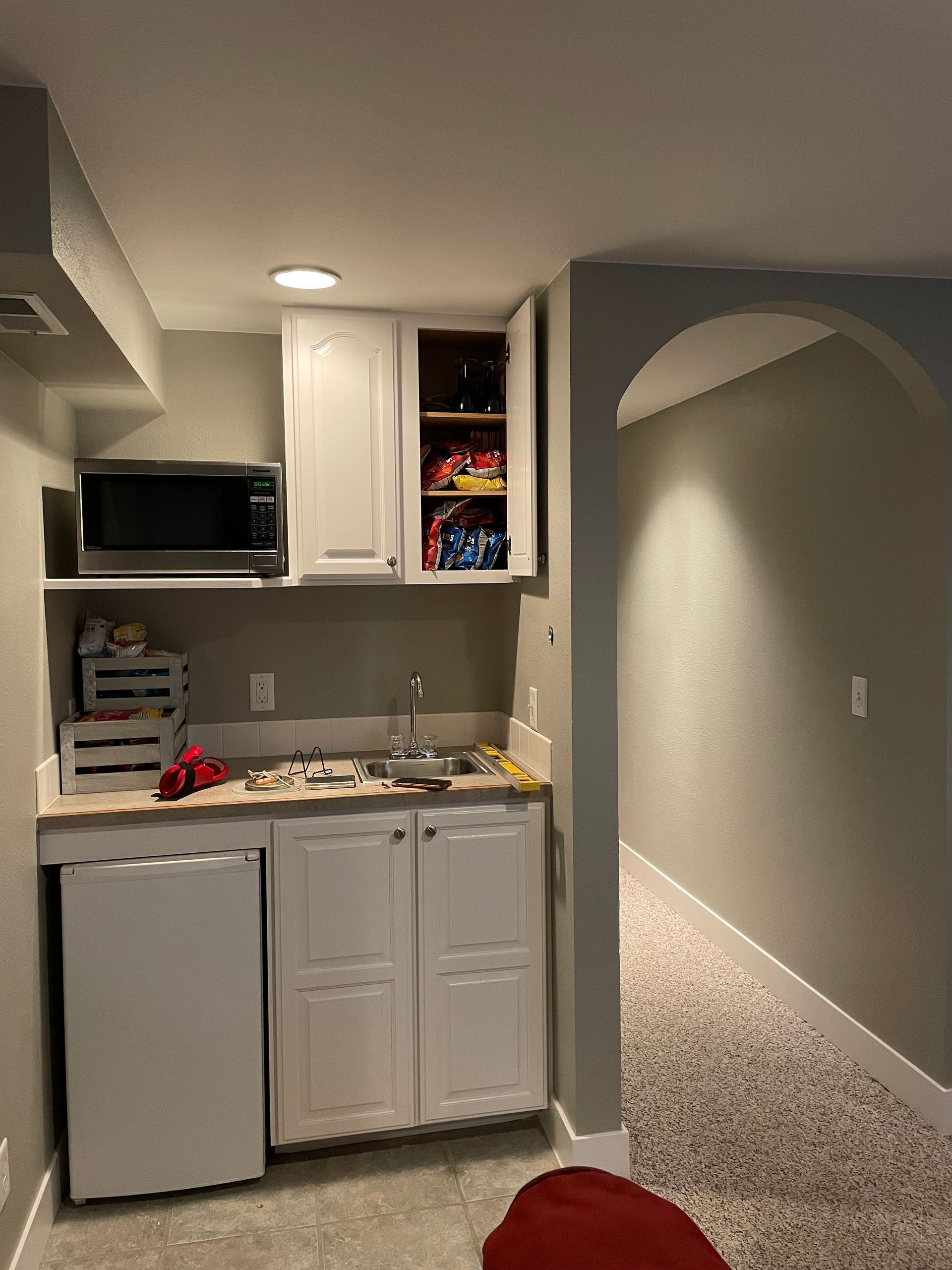 A Kitchen With White Cabinets , A Sink , A Microwave And A Refrigerator