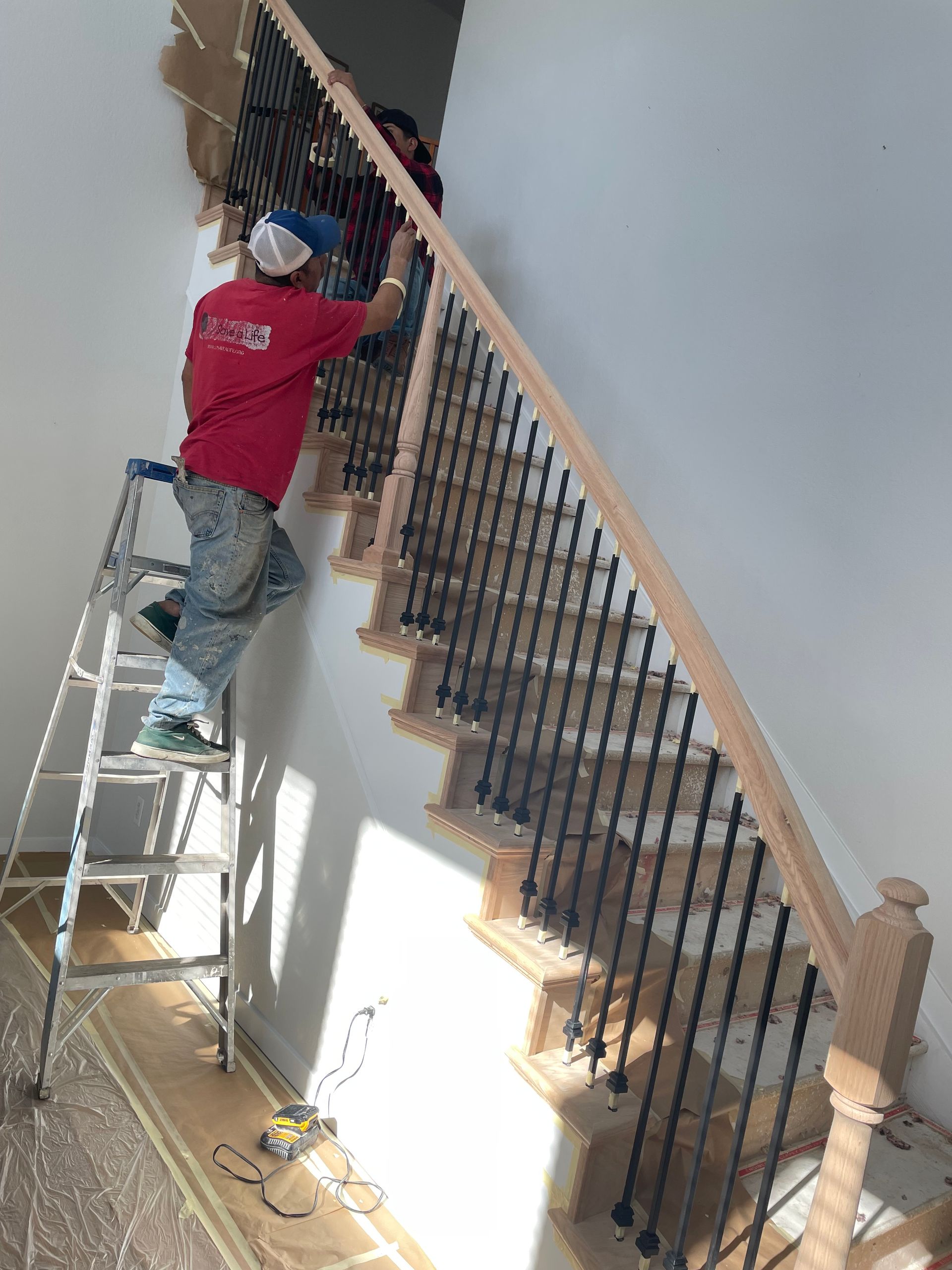 A Man Is Standing On A Ladder Painting A Wall Next To A Staircase