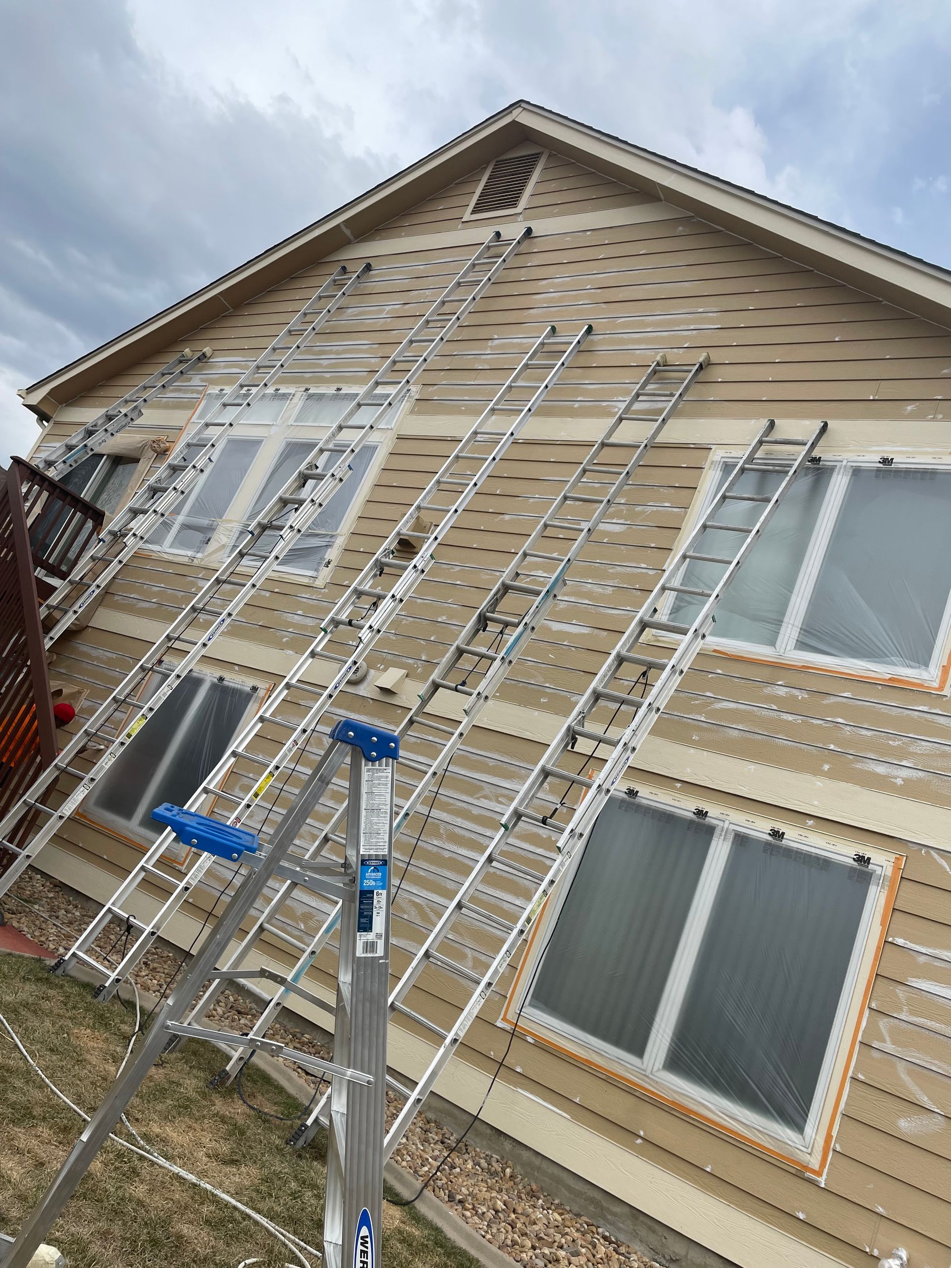 A Row Of Ladders Are Sitting In Front Of A House Being Painted