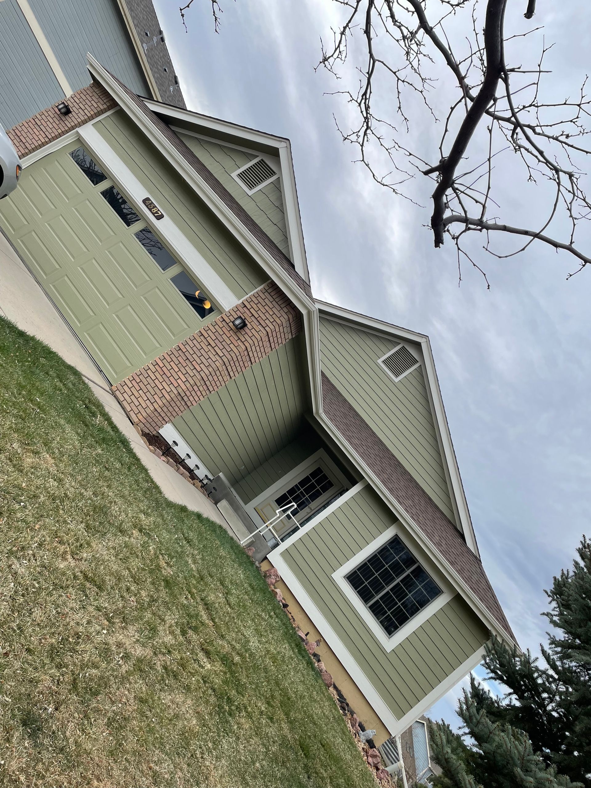 A House With A Green Siding And A Brown Roof