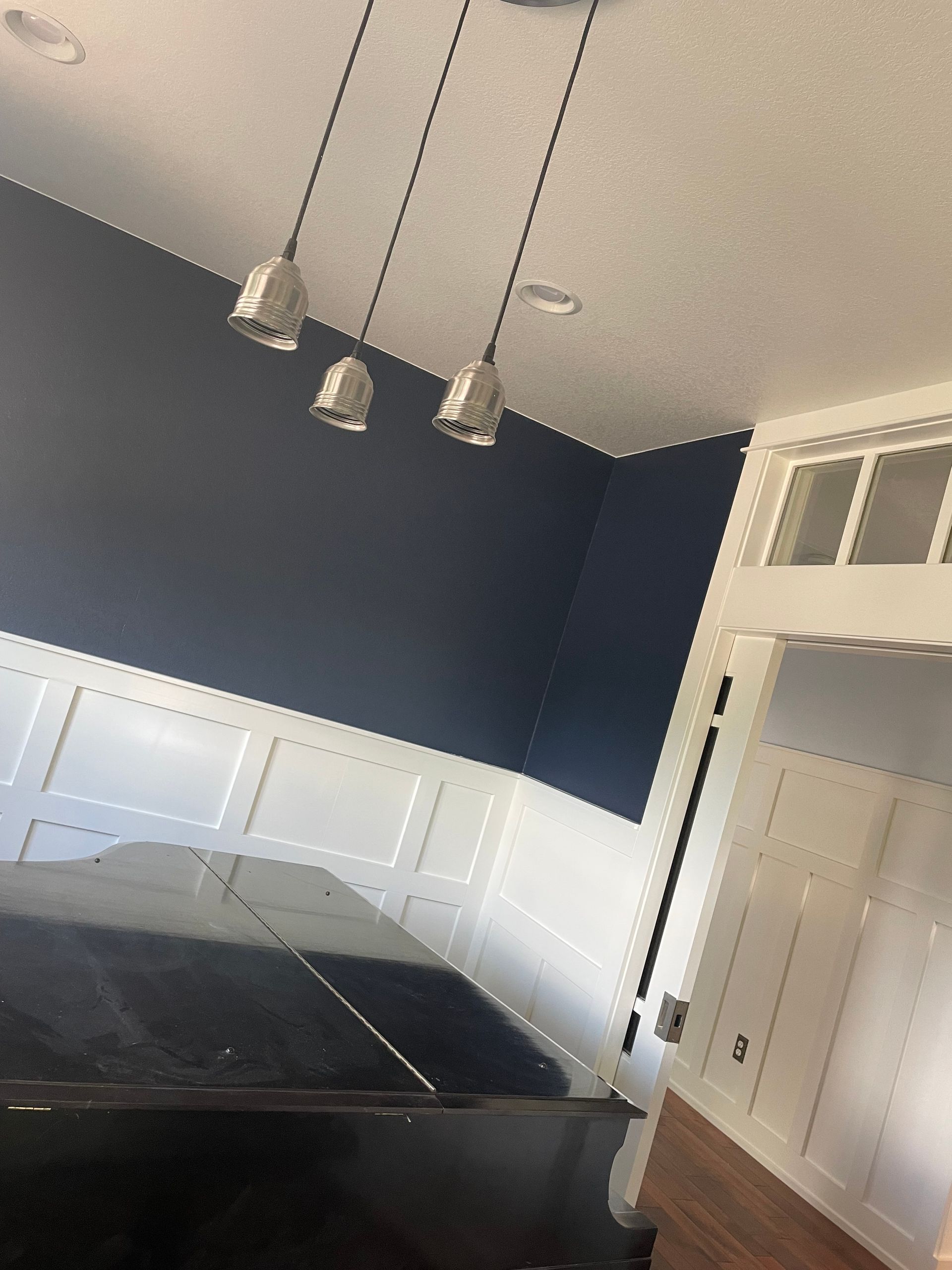 A Room With Blue Walls And White Trim Has Three Pendant Lights Hanging From The Ceiling