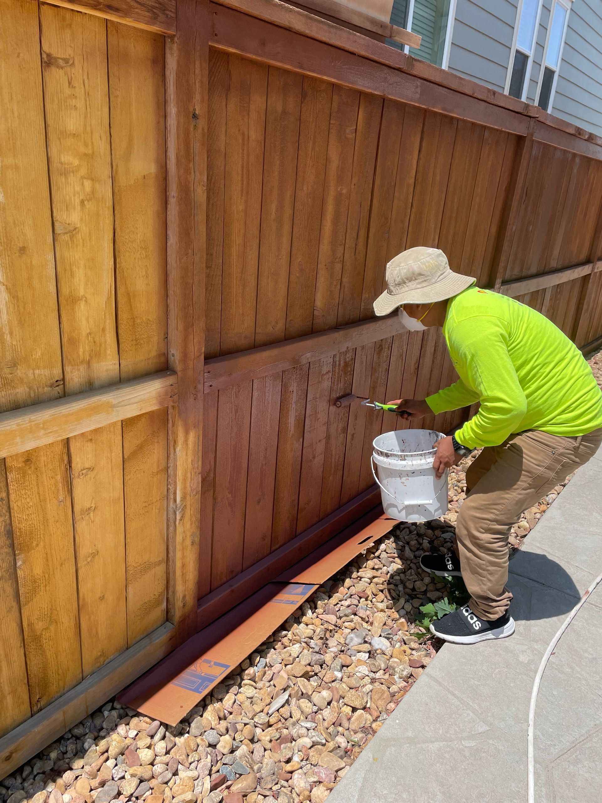 A Man Is Painting A Wooden Fence With A Brush