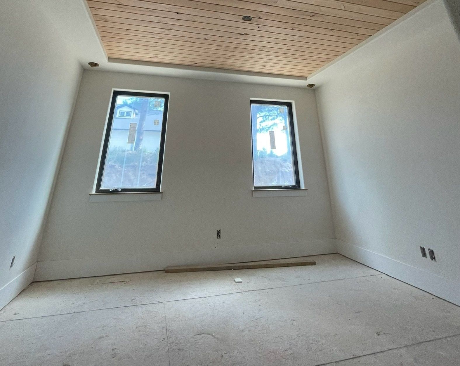 An Empty Room With Two Windows And A Wooden Ceiling