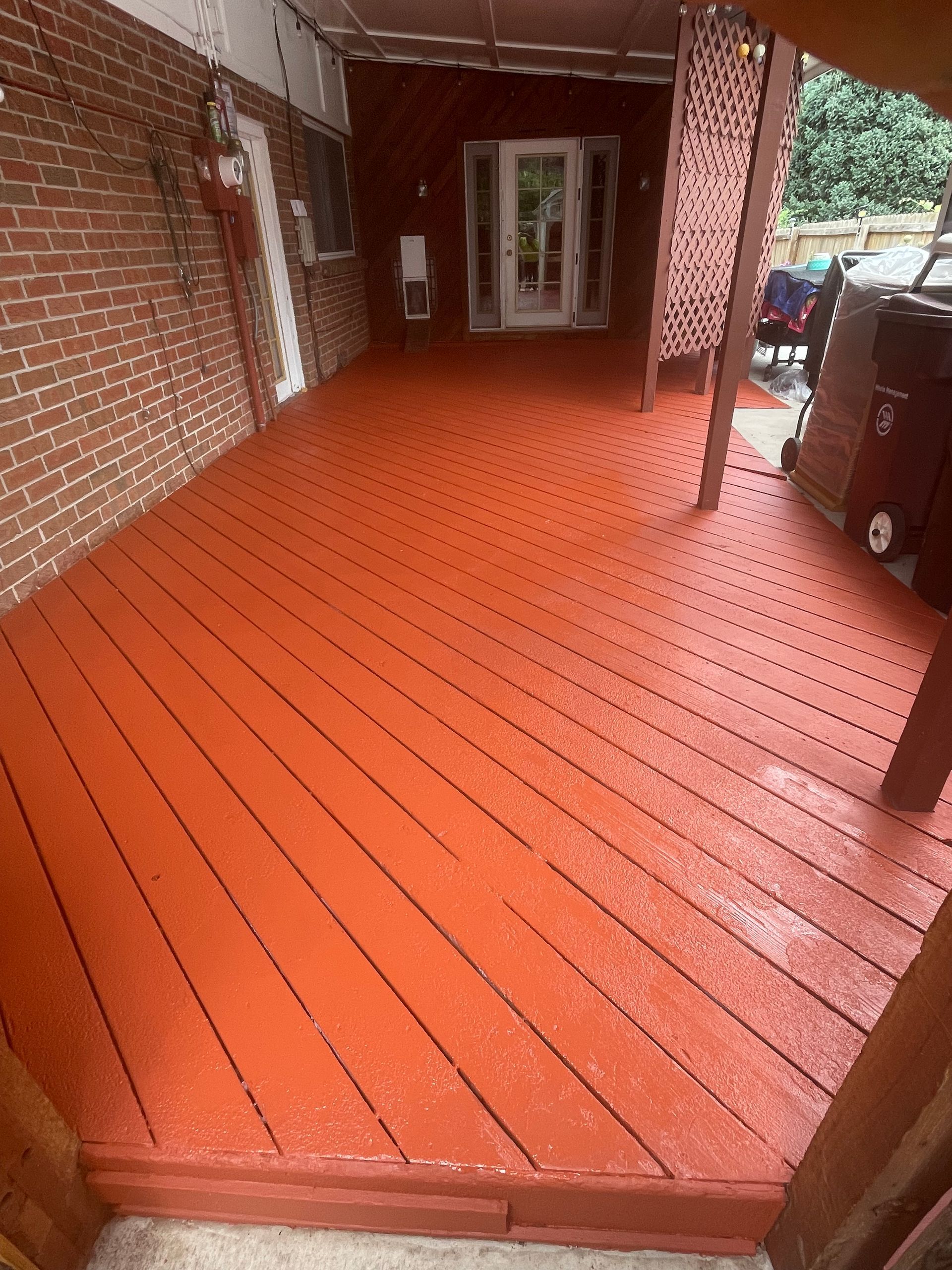 A Red Wooden Deck With A Brick Wall In The Background