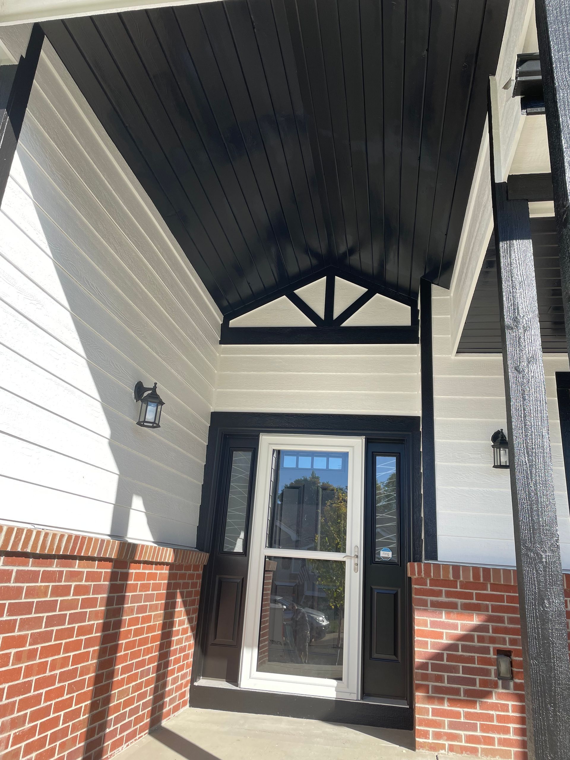 The Front Porch Of A House With A Black Ceiling And A White Door