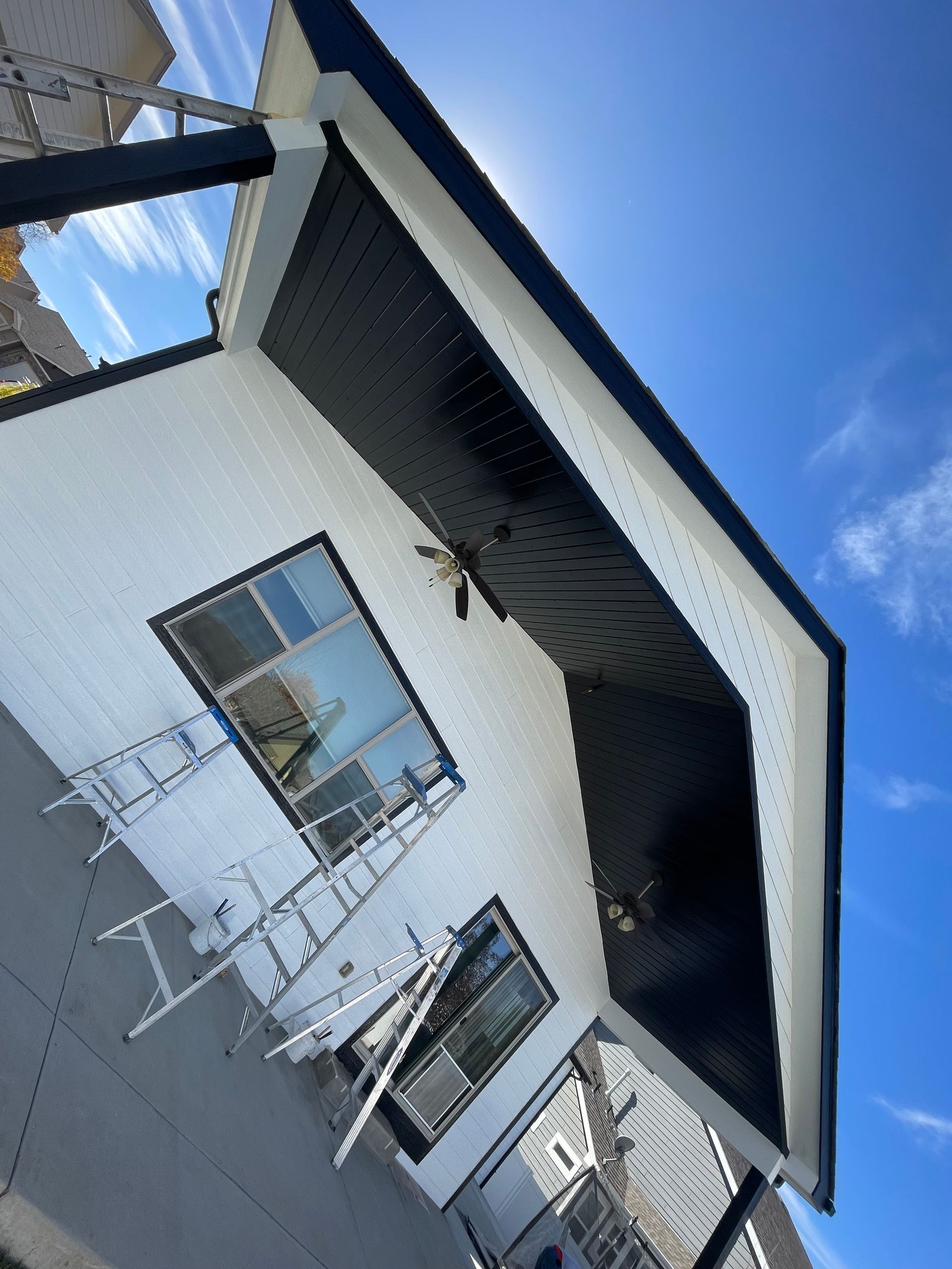 A White House With A Black Roof And A Blue Sky In The Background