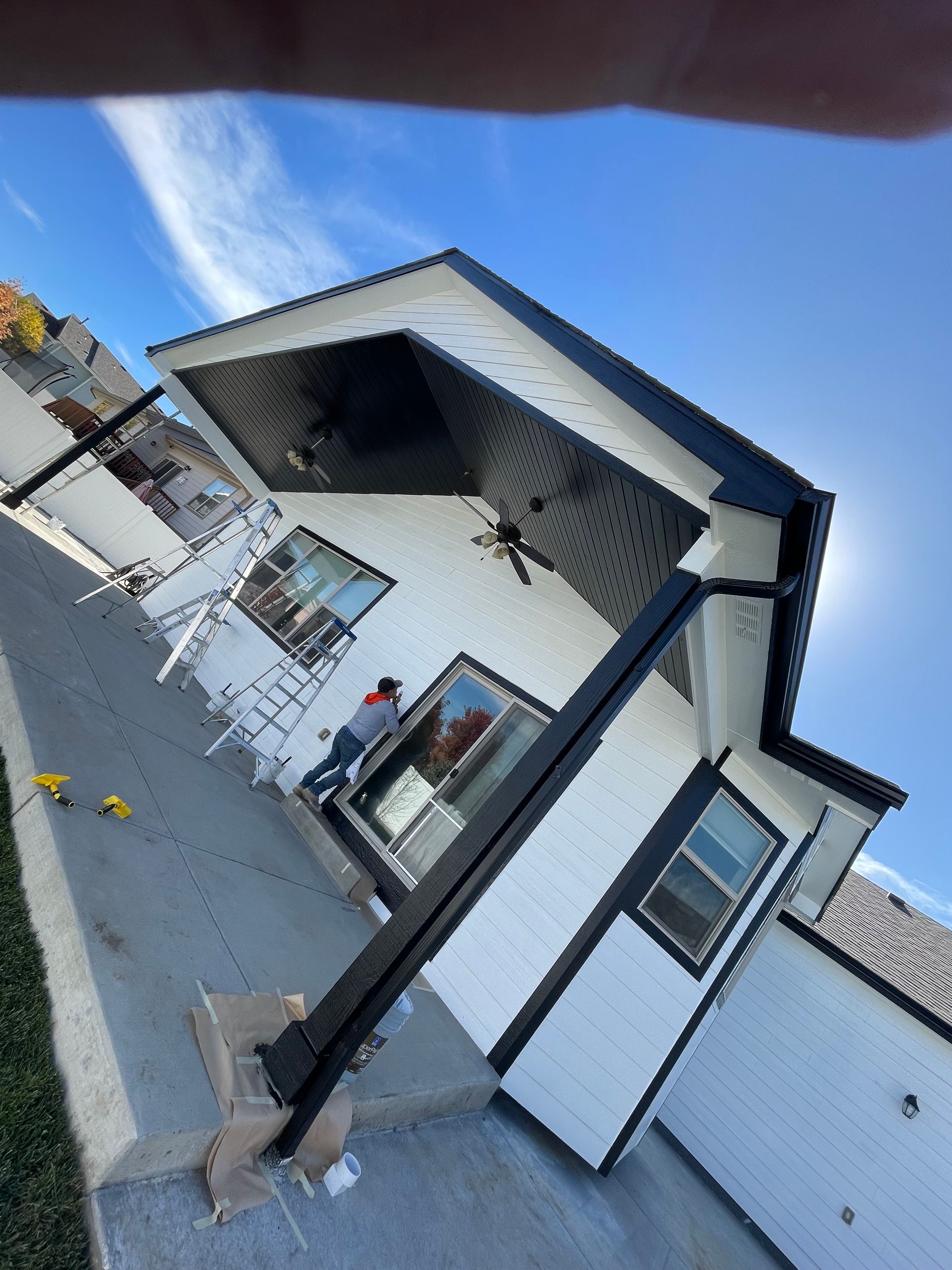 A Person Is Standing In Front Of A White House With A Black Roof