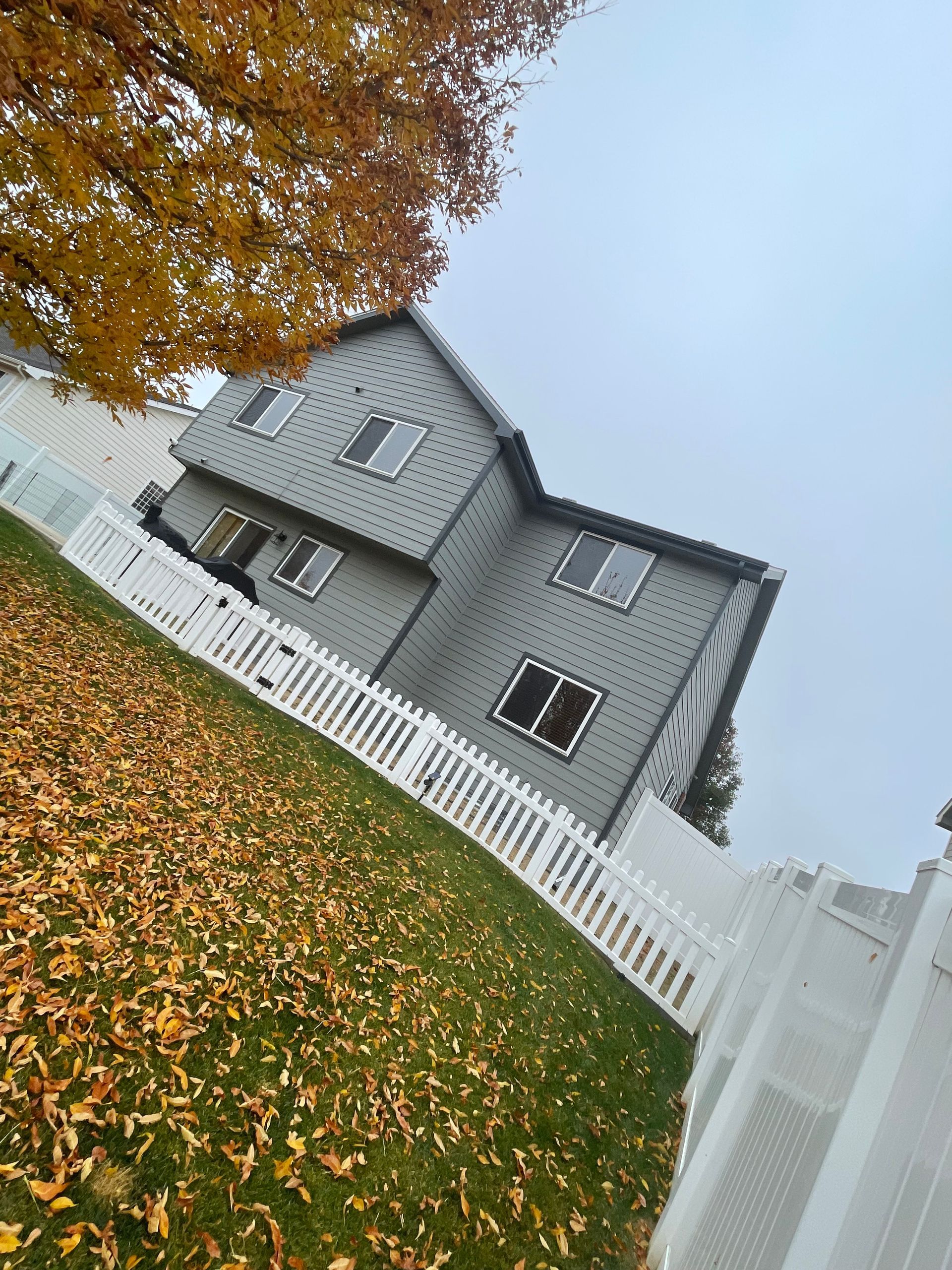 A House With A White Picket Fence And A Tree In Front Of It