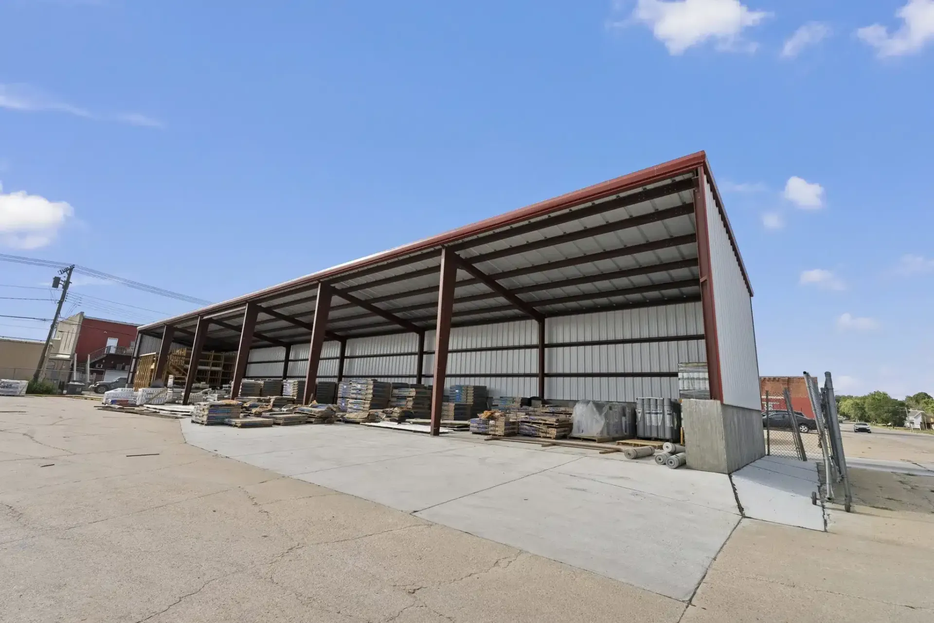a large metal building with a red roof is sitting in the middle of a dirt field .