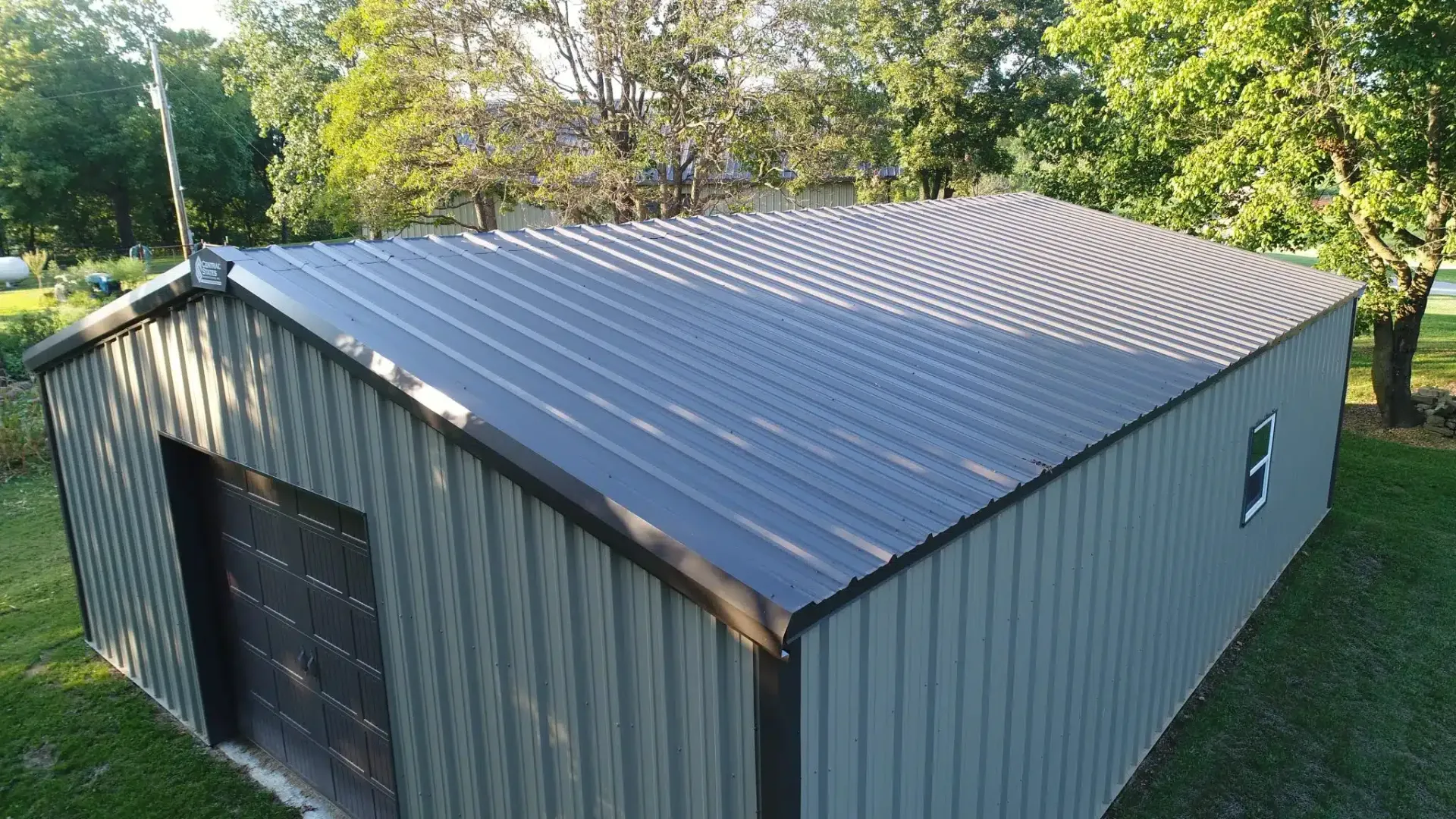 a garage with a metal roof is sitting in the middle of a grassy field .