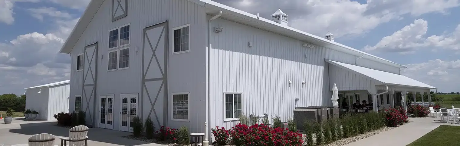 a large white barn is sitting on top of a lush green field .