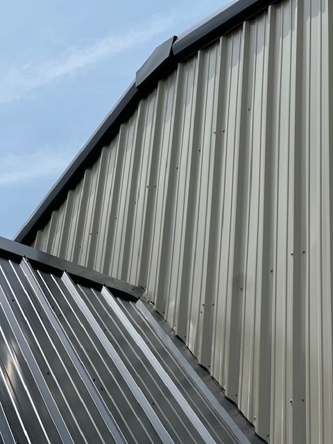 Close-up of gray corrugated metal building roofs against a blue sky