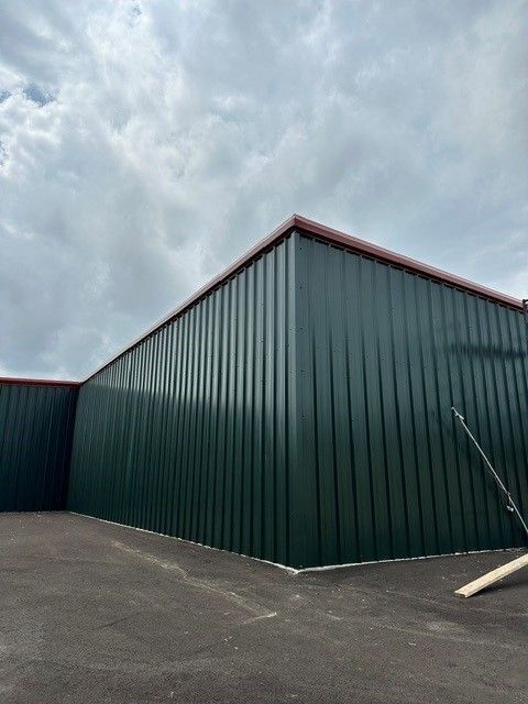Dark green corrugated metal building under a cloudy sky