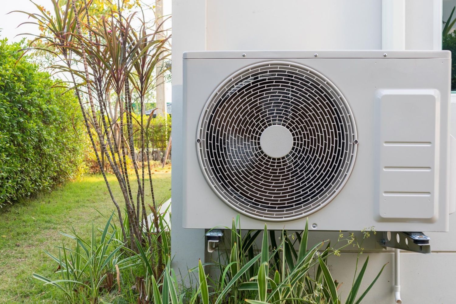 A white air conditioner is mounted on the side of a building.