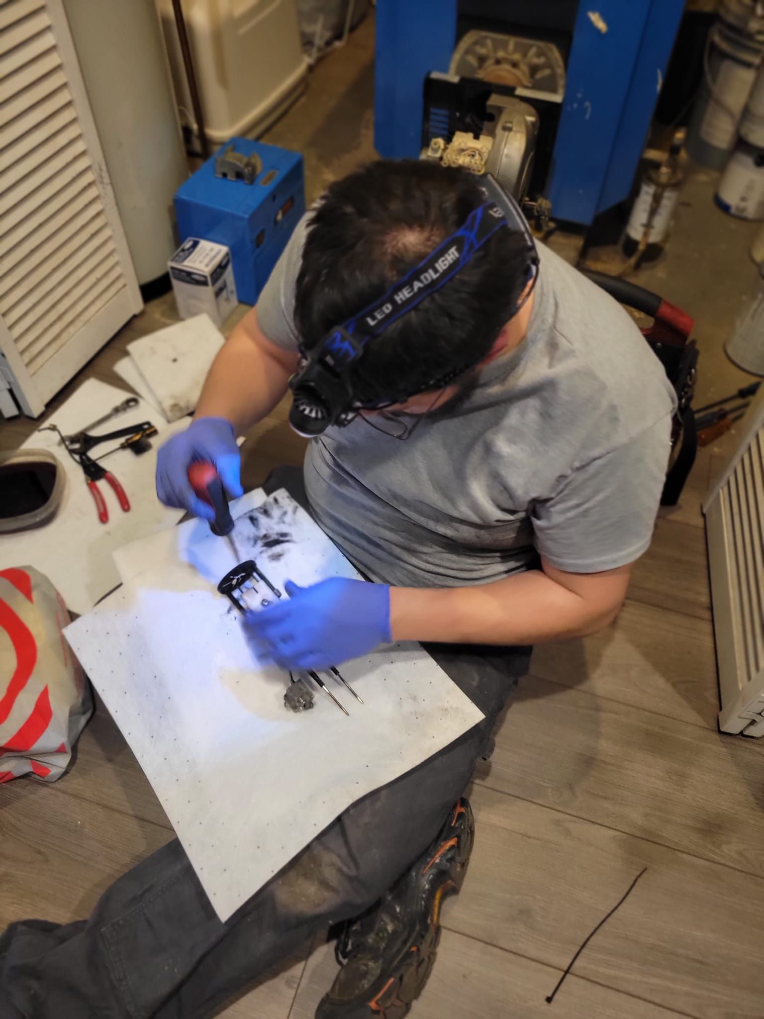 A man wearing a headlamp is working on a piece of equipment.