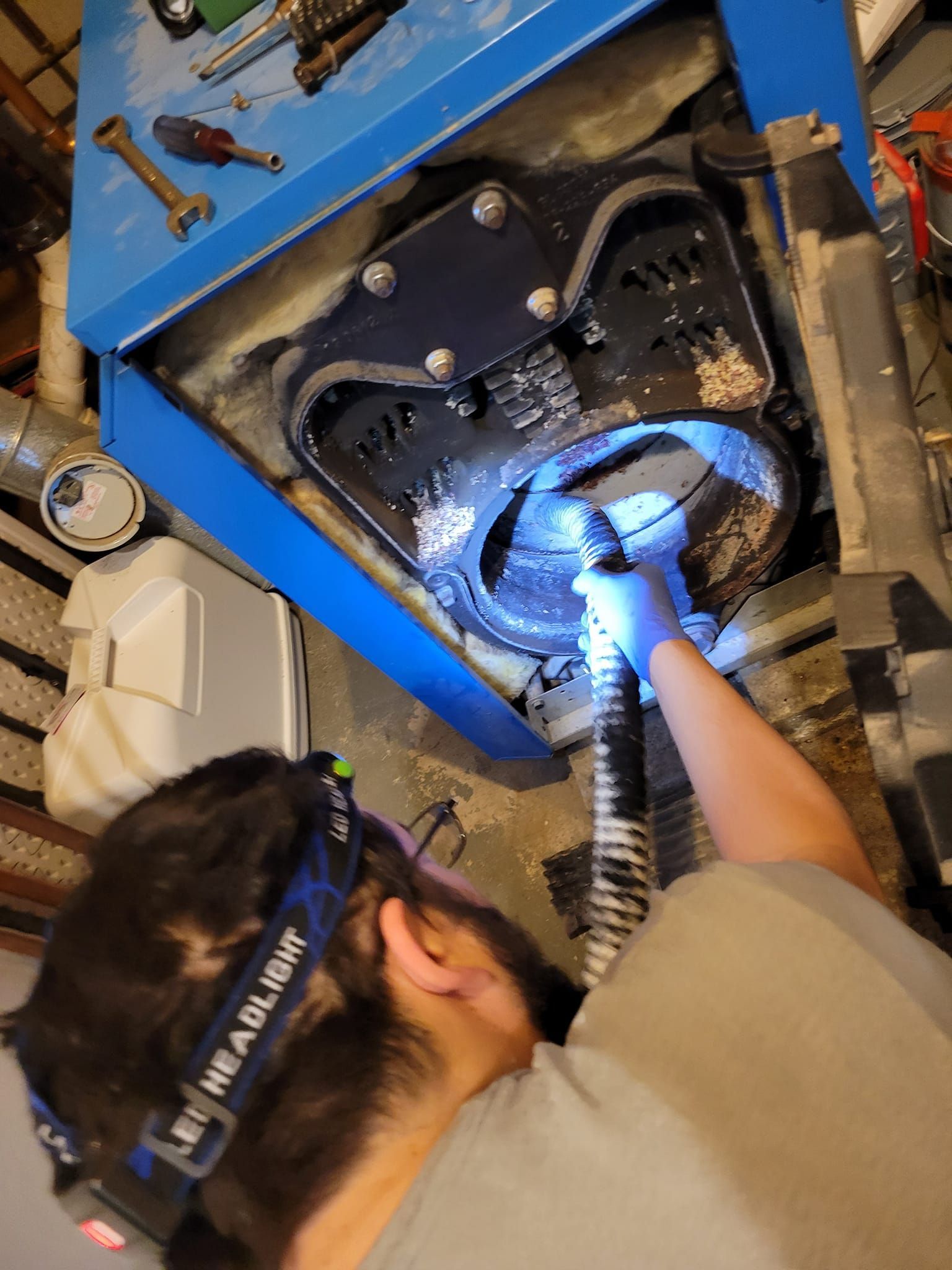 A man is holding two gauges in front of an air conditioner.