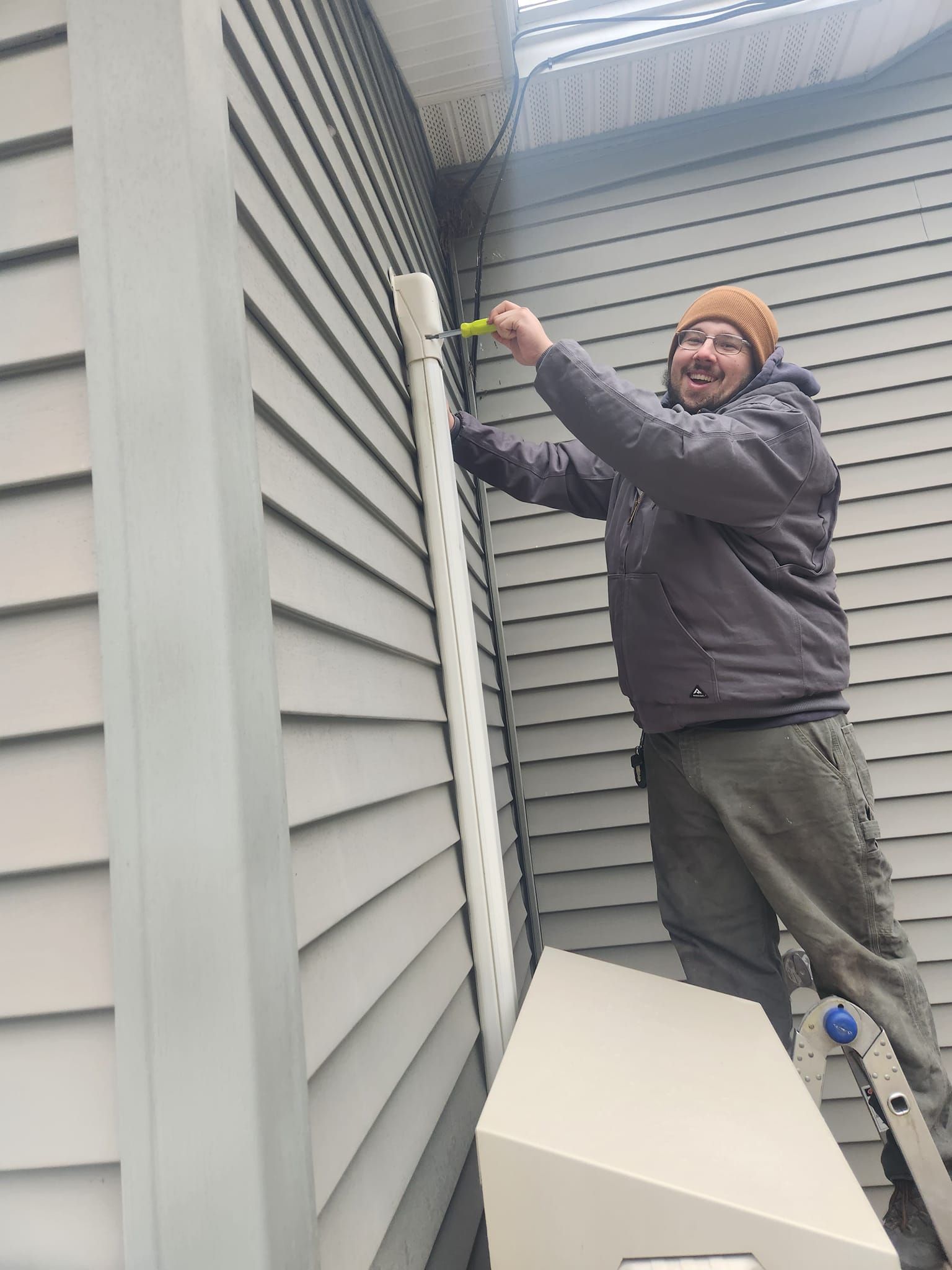 A person is fixing an air conditioner with a screwdriver.