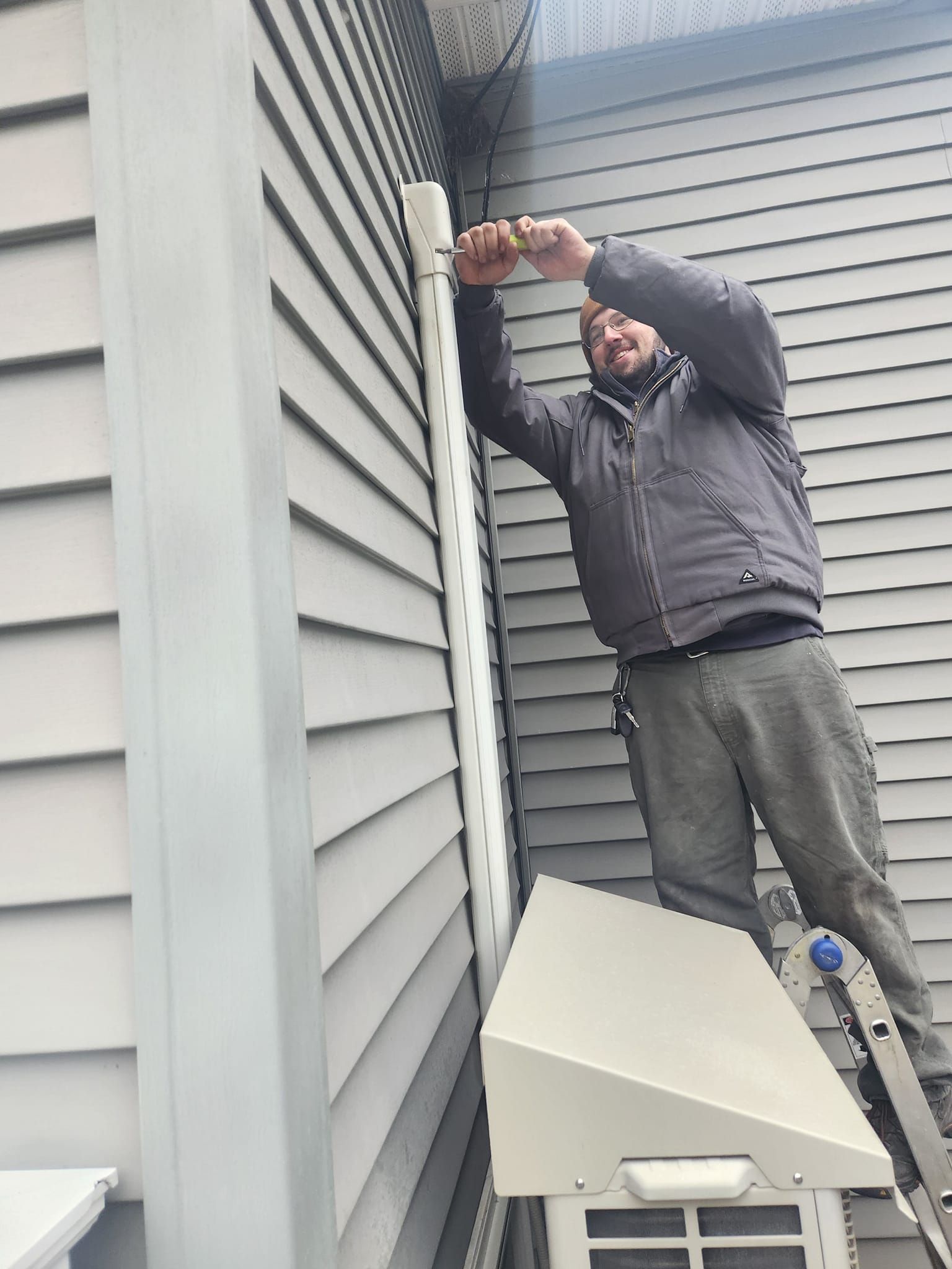 A man is working on an air conditioner outside of a building.