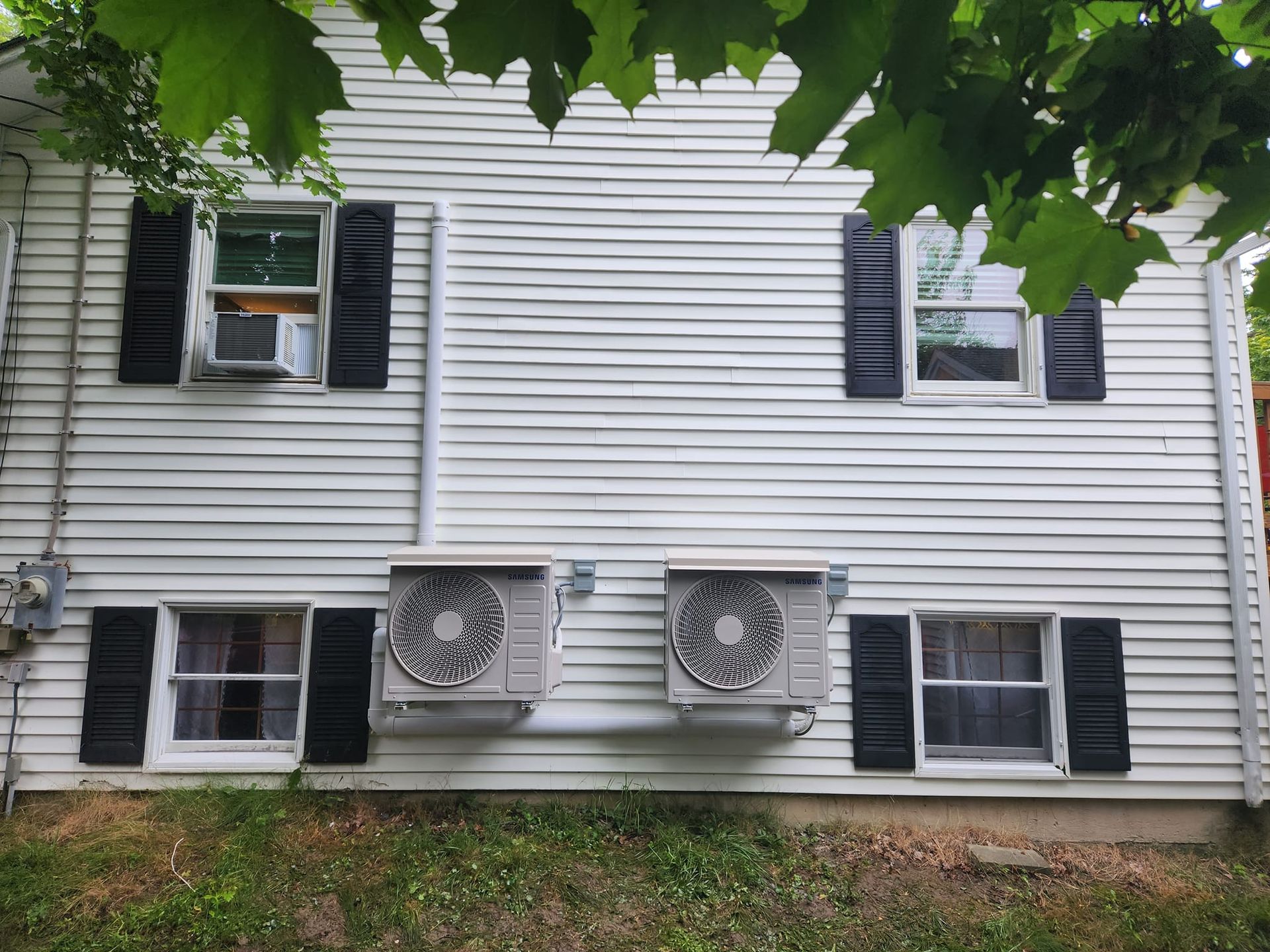 A row of air conditioners are sitting outside of a building.