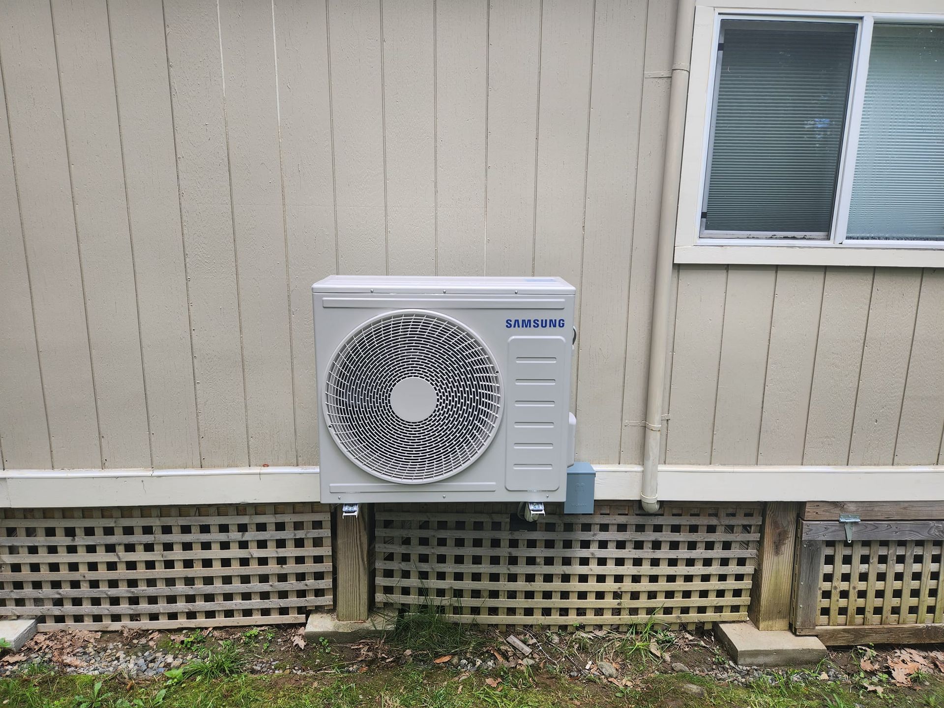 A man is fixing an air conditioner in a kitchen while holding a clipboard.