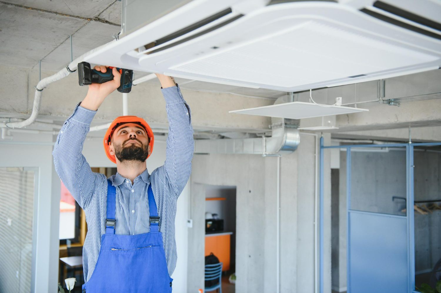 A man is installing a ceiling fan in an office.
