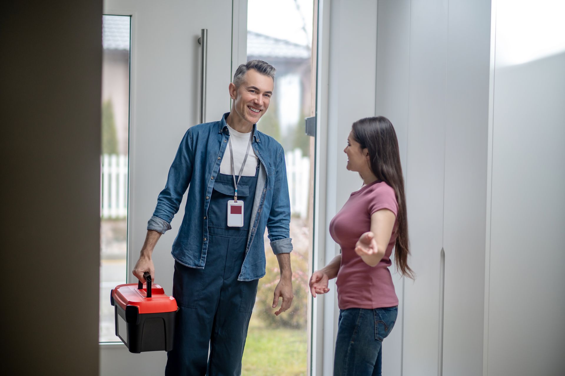 A man is holding a toolbox and talking to a woman.