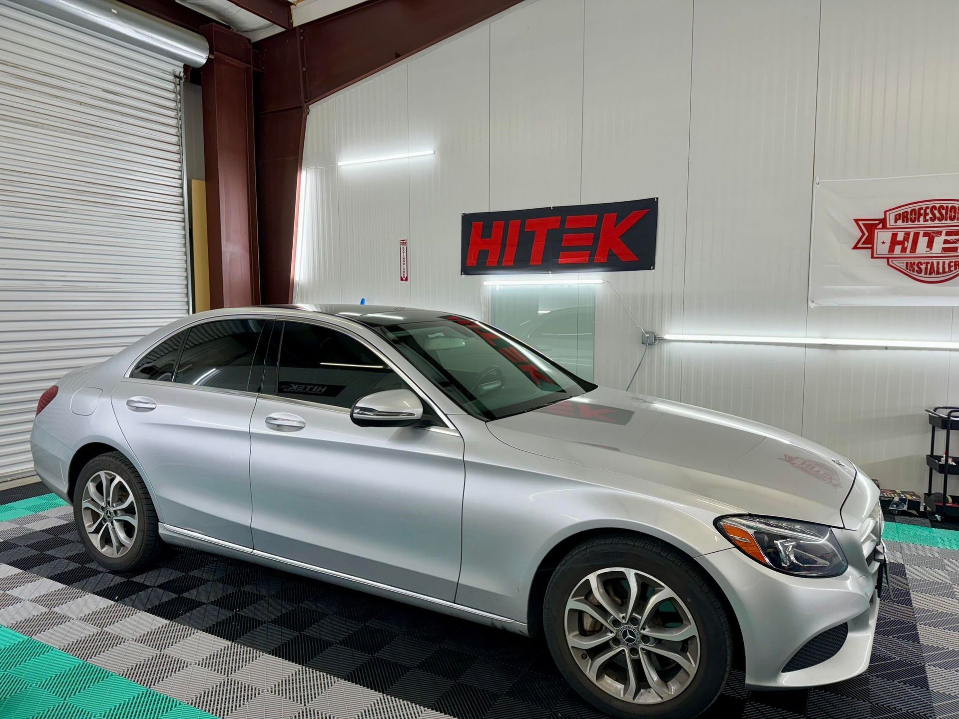 A silver mercedes benz c class is parked in a garage.