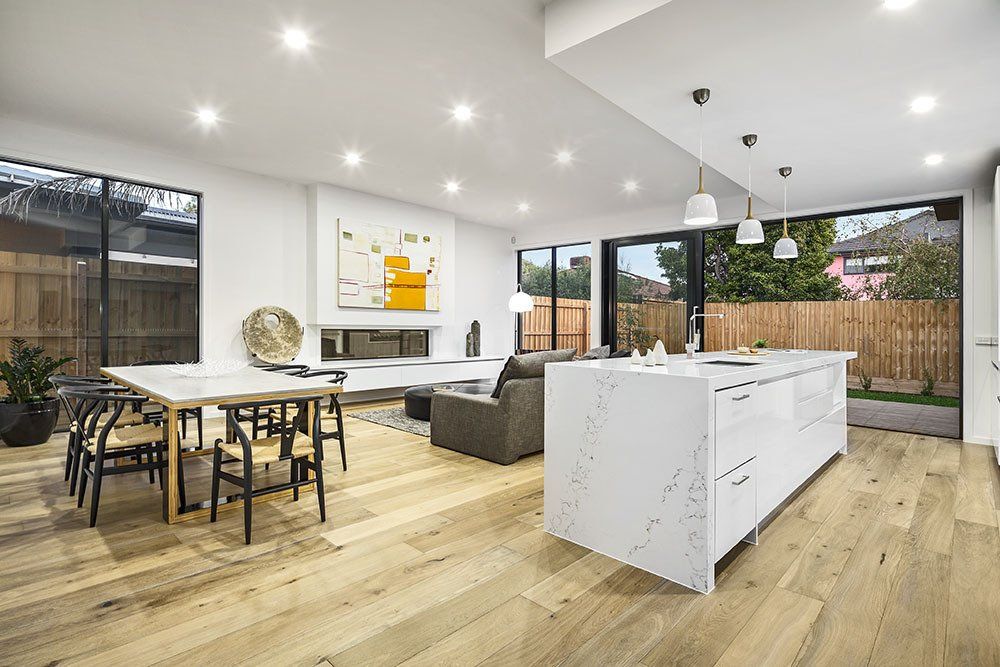 A living room with a table and chairs and a kitchen with a large island.