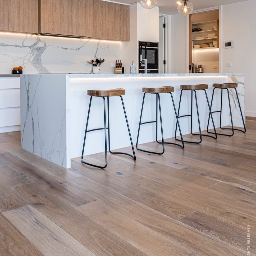 A kitchen with a large island and wooden stools.