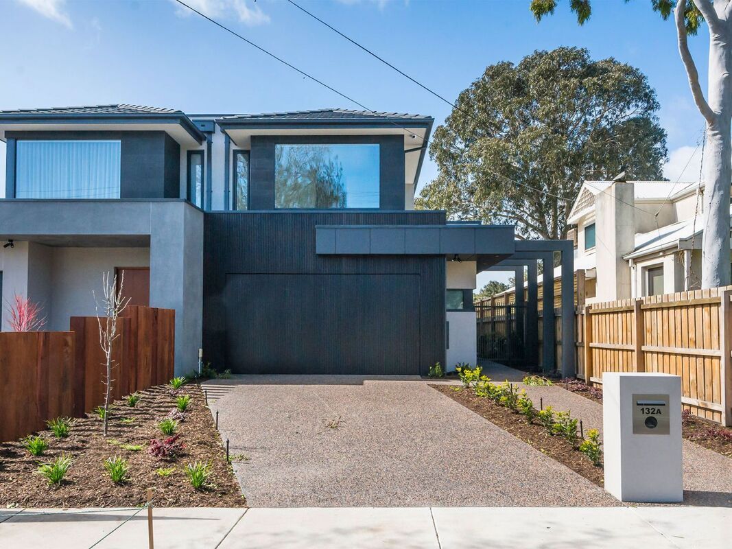 A large house with a driveway and a wooden fence in front of it.
