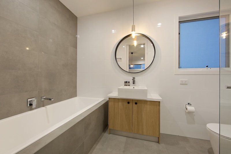 A bathroom with a bathtub , sink , toilet and mirror.