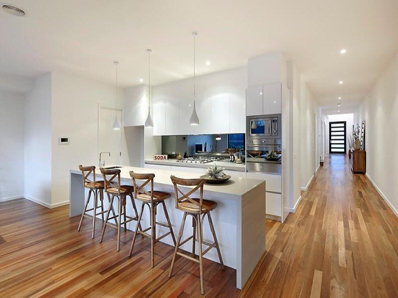 A kitchen with a long island and wooden floors