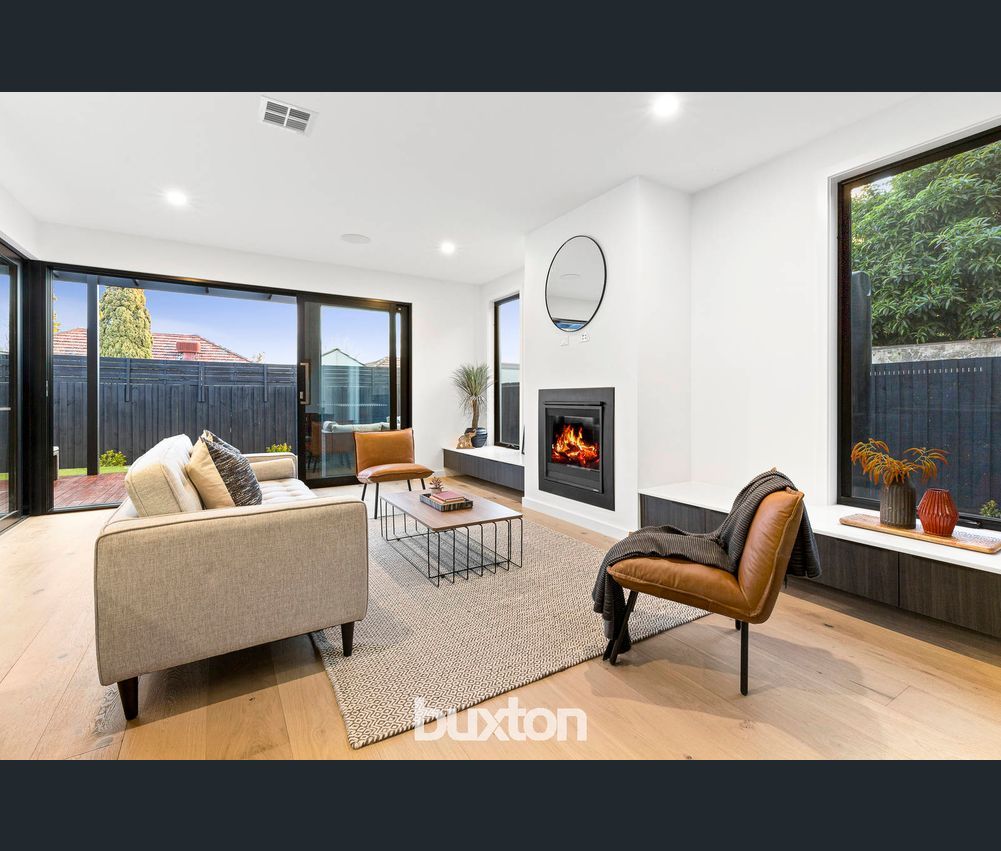 A living room with a couch , chair , coffee table and fireplace.
