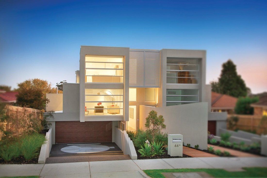 A modern house with a lot of windows and a driveway.