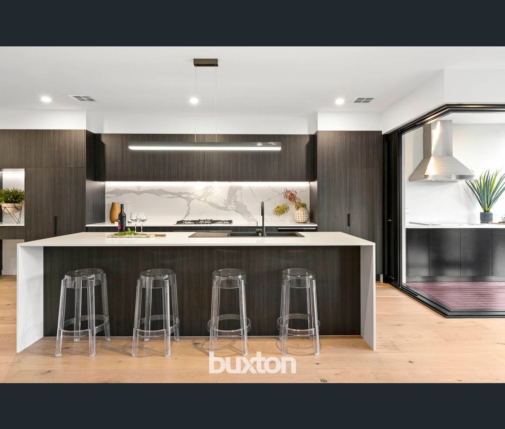 A kitchen with a large island and stools by buxton