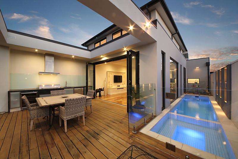 A house with a swimming pool and a table and chairs on the deck