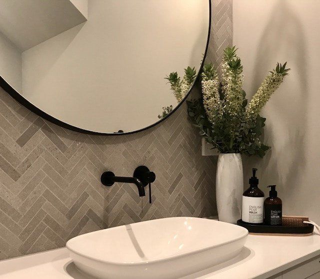 A bathroom with a sink and a round mirror