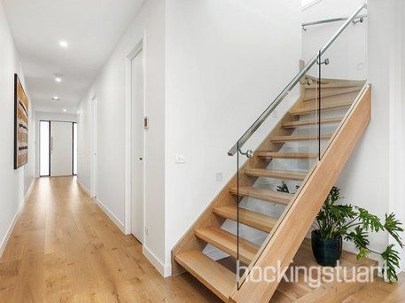 A wooden staircase with a glass railing in a hallway.